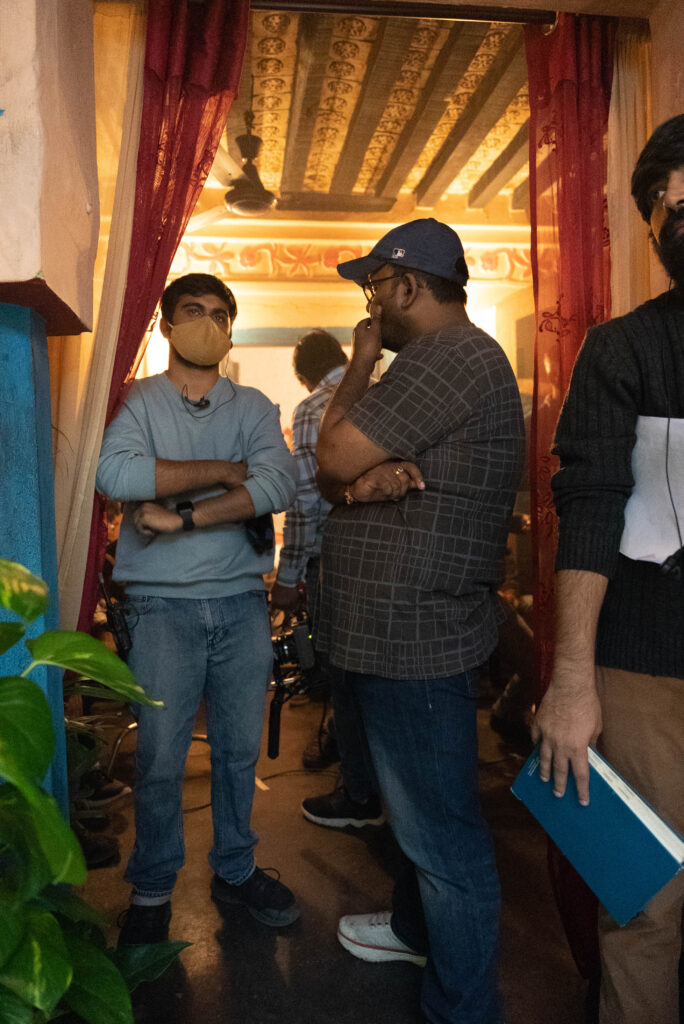 Kartik Parmar the cinematographer (wearing the mask) discussing a shot with Dibakar Das Roy (Writer, Director)